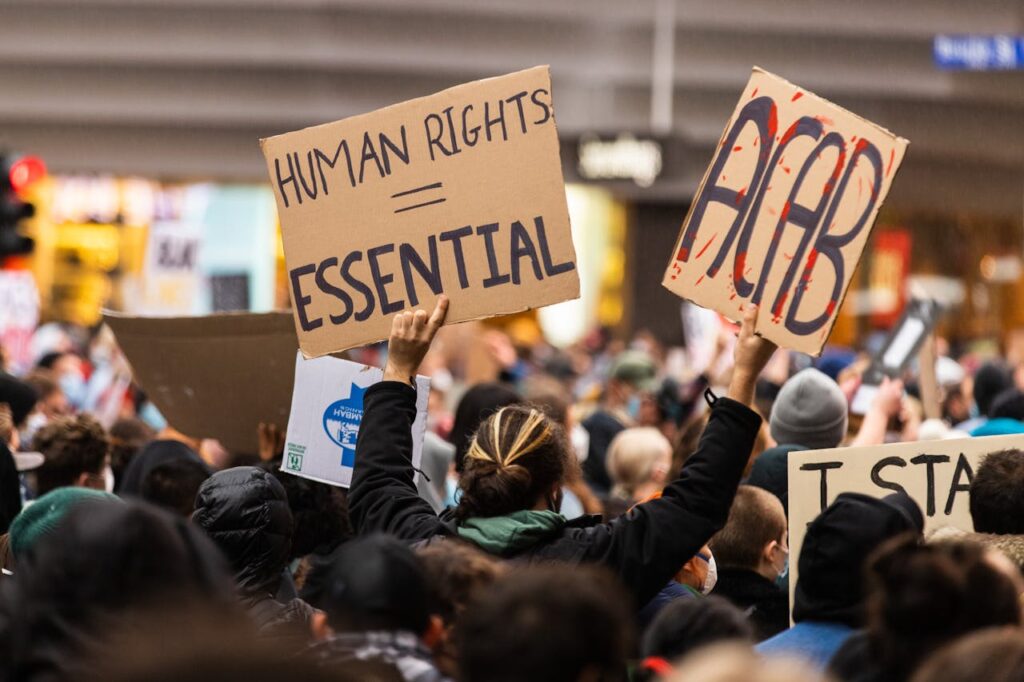 A crowd gathers in Melbourne for a protest advocating human rights, holding signs with powerful messages.
