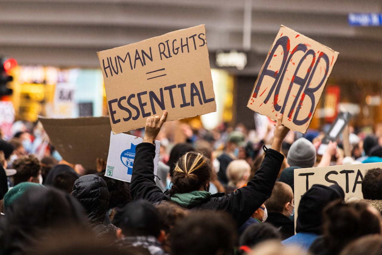 A crowd gathers in Melbourne for a protest advocating human rights, holding signs with powerful messages.